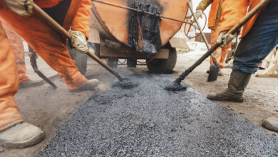 Workers repairing the road with shovels fill asphalt driveway repair