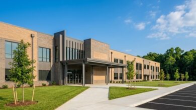 A newly completed suburban middle school building with fresh landscaping on a clear summer morning