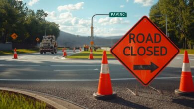 Orange ROAD CLOSED detour sign and traffic cones at a Murfreesboro parkway intersection with a paving crew at work