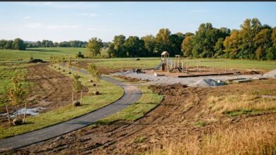 A new community park under construction with a fresh paved trail, young trees and a partly built playground (illustrative)