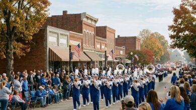 Marching band and spectators at a college homecoming parade on a small-city street (illustrative)
